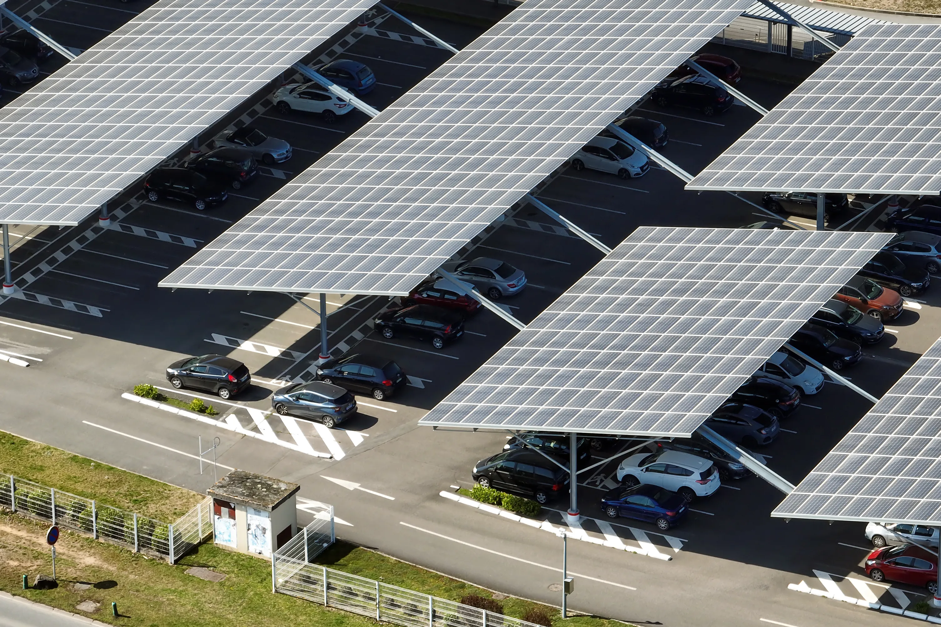 Aerial view of solar panel canopies covering the parking bays of a full car park